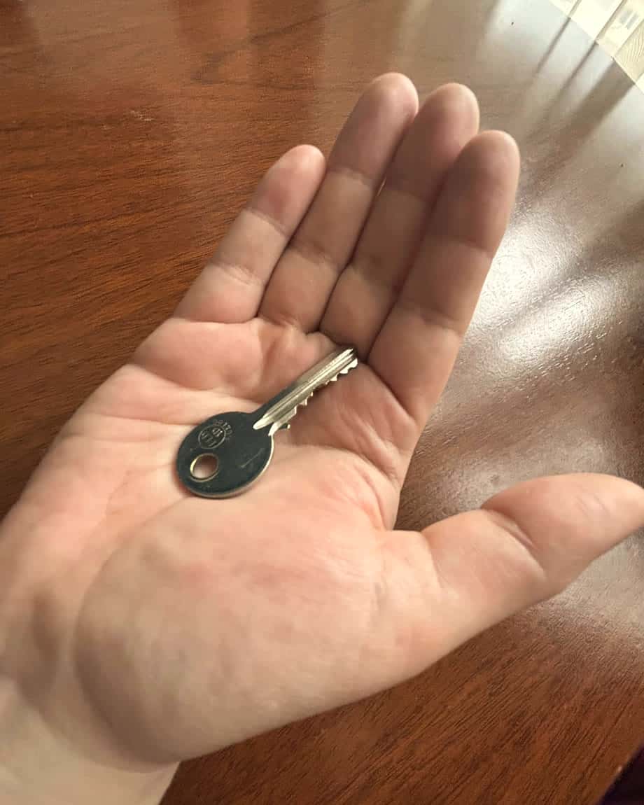 Una llave en la palma de una mano abierta, sobre una mesa de madera