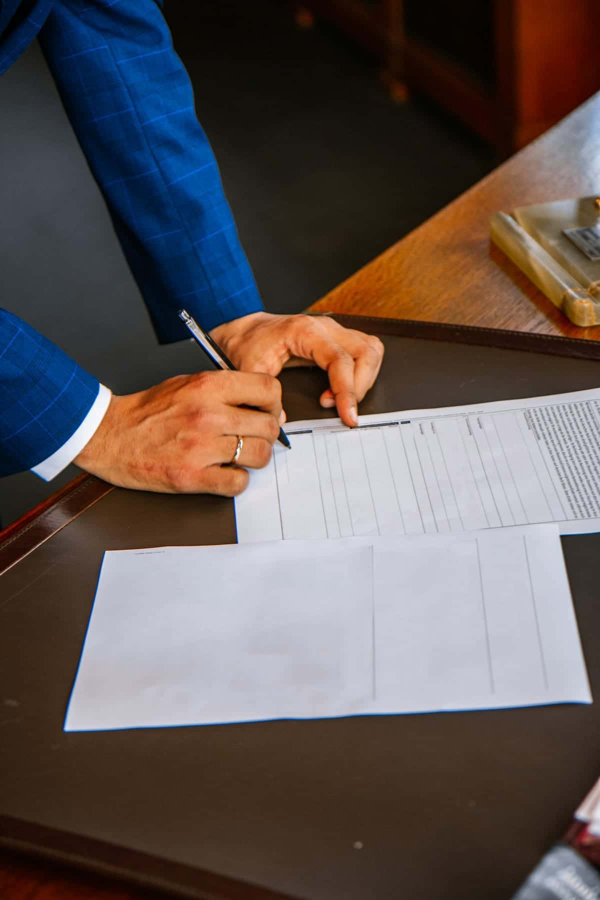 Unas manos completando un formulario con un lápiz, sobre una mesa